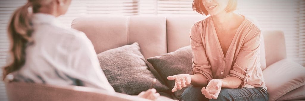 Two women having a conversation on a couch
