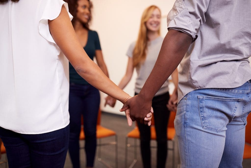 Group therapy standing in a circle holding hands