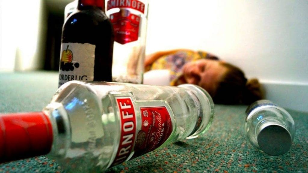 alcoholic on the ground with a bottle of vodka