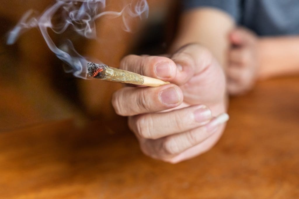 male holding cannabis joint with blurred background